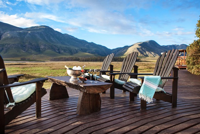 An outdoor seating area at Mosaic, overlooking the Hermanus Lagoon and the mountain range beyond